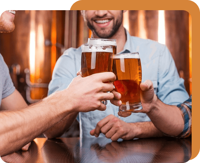 A group of people holding beer glasses at a table.