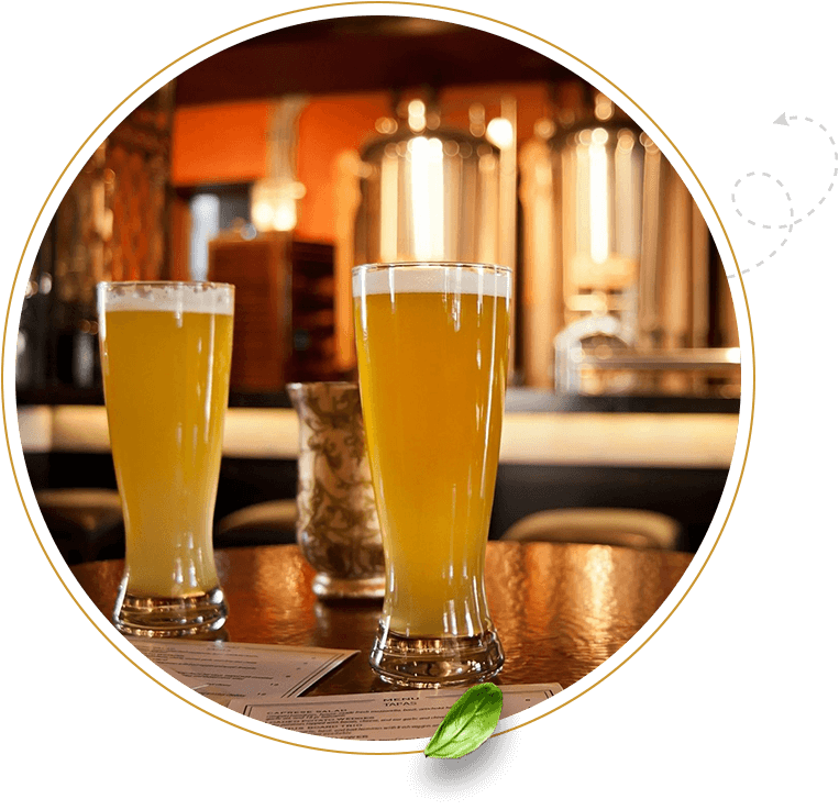 Two glasses of beer on a table in front of a bar.